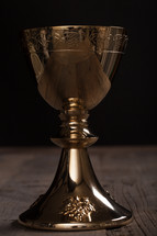 A golden wine goblet on a wooden surface.