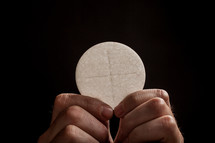 Hands holding a communion wafer.