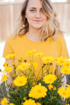 a woman standing behind yellow flowers 