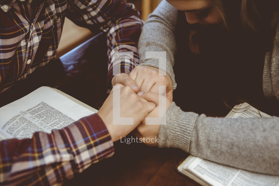 a couple holding hands and reading the Bible together 