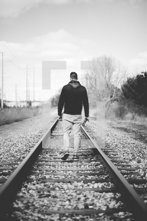 man walking in the middle of train tracks
