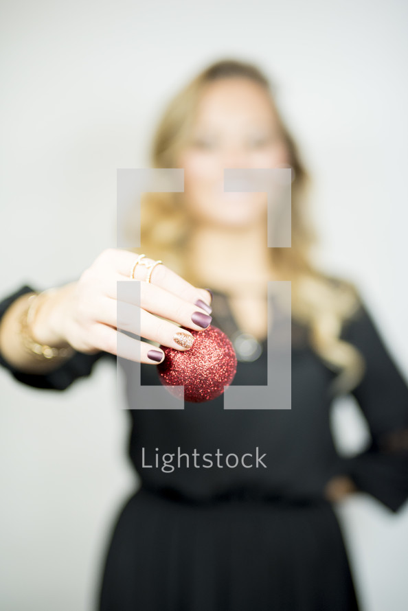 woman holding a red Christmas ornament 