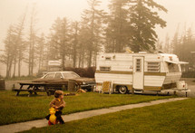 vintage image of a toddler boy and camper at a campsite 