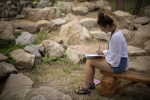 girl sitting outdoors reading her Bible 