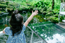 a little girl feeding fish in a koi pond 