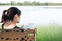 a woman sitting on a park bench reading a Bible 