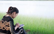 a woman praying outdoors on a park bench 