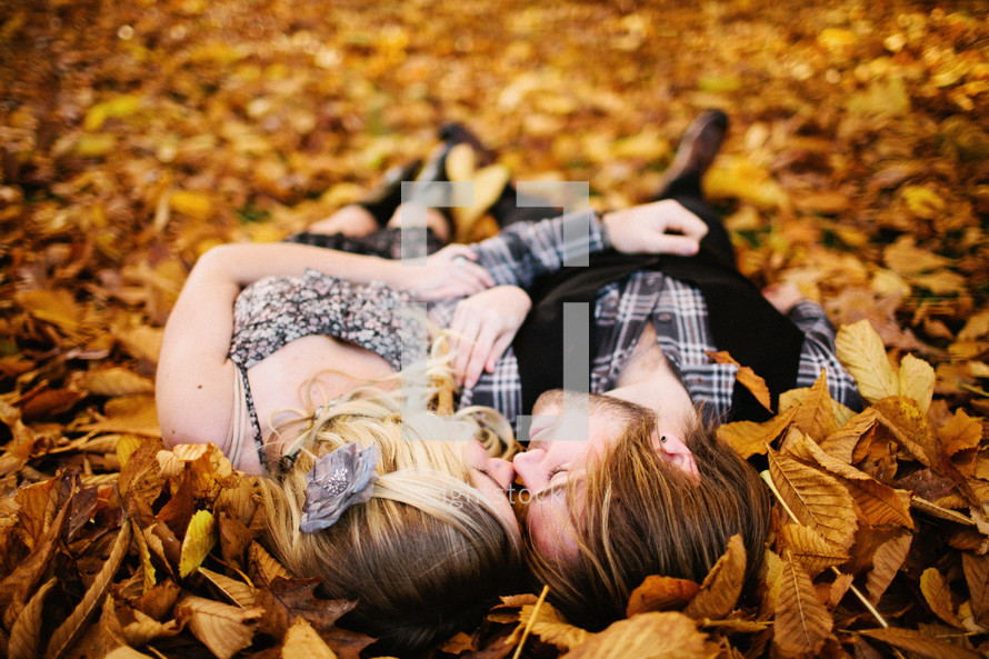 couple lying in a pile of leaves