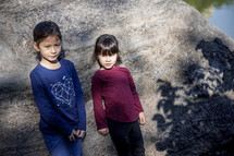 Little girls standing in front of a rock