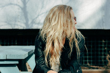a woman with long blonde hair sitting outdoors 