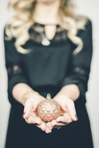 woman holding a gold Christmas ornament 