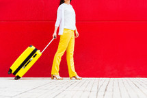 woman with a yellow suitcase walking down the street.