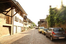 cars parked along a cobblestone street 