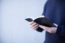 torso of a man reading a Bible 
