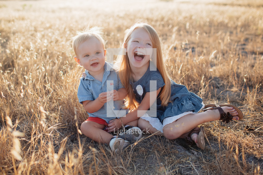 siblings hugging in a field 