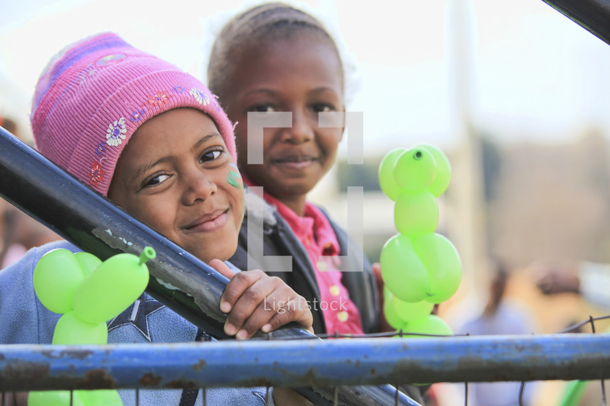 Little girls smiling and holding balloons