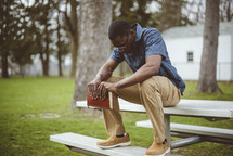 a man sitting holding a Bible praying 