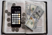 money, calculator app, on the page of a Bible 