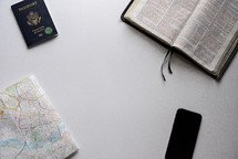 map, passport, cellphone, and Bible on a white background 