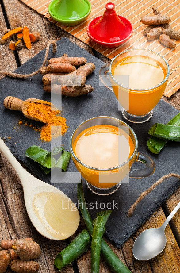 Hot drink with aloe vera and turmeric. Glass cups on a slate tray