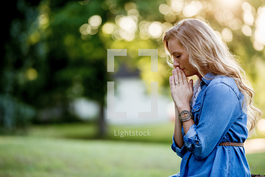 a woman outdoors praying 
