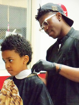A young boy gets a hair cut at a local church sponsored event offering free hair cuts as a ministry and service to the community.  