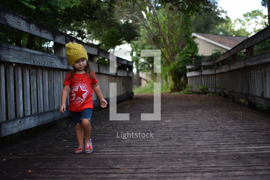 toddler girl walking on a wooden path in summer 