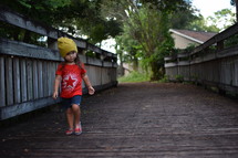 toddler girl walking on a wooden path in summer 
