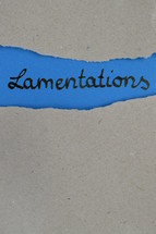 Lamentations - torn open kraft paper over blue paper with the name of the prophetic book Lamentations
