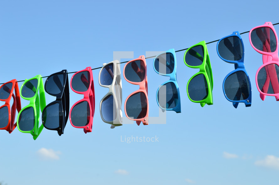 sunglasses hanging on a wire against a blue sky 