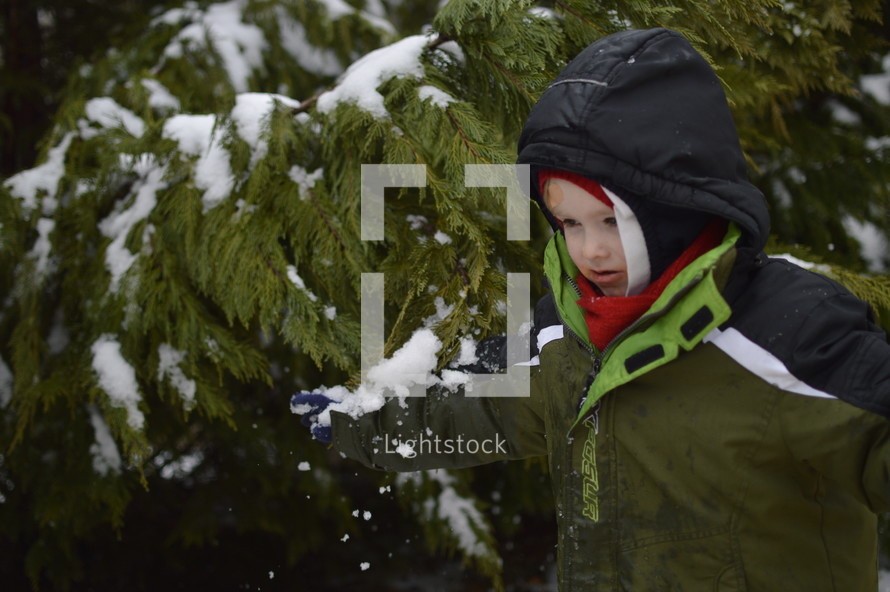 boy child in a winter coat standing in snow 