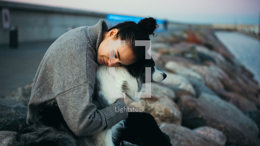 Woman with her dog sitting on rocks