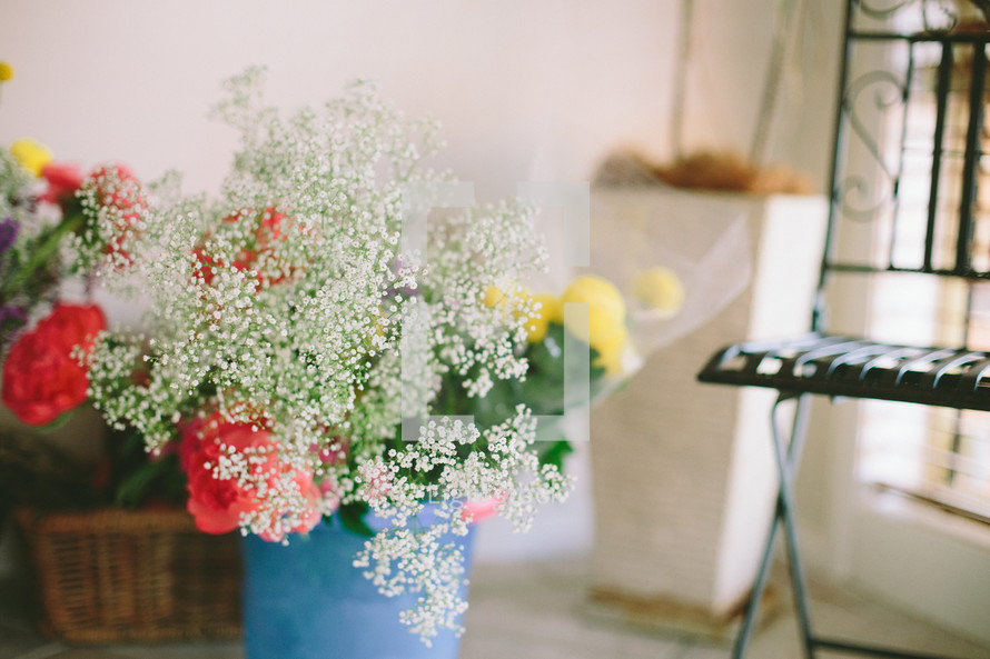 Bouquet of flowers in a vase near a chair.