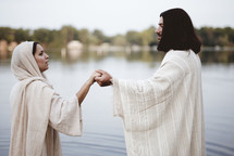 Jesus standing in water reaching towards a woman 