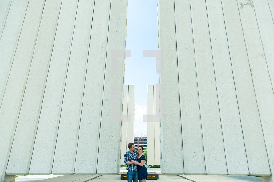 a couple embracing standing outdoors between buildings 