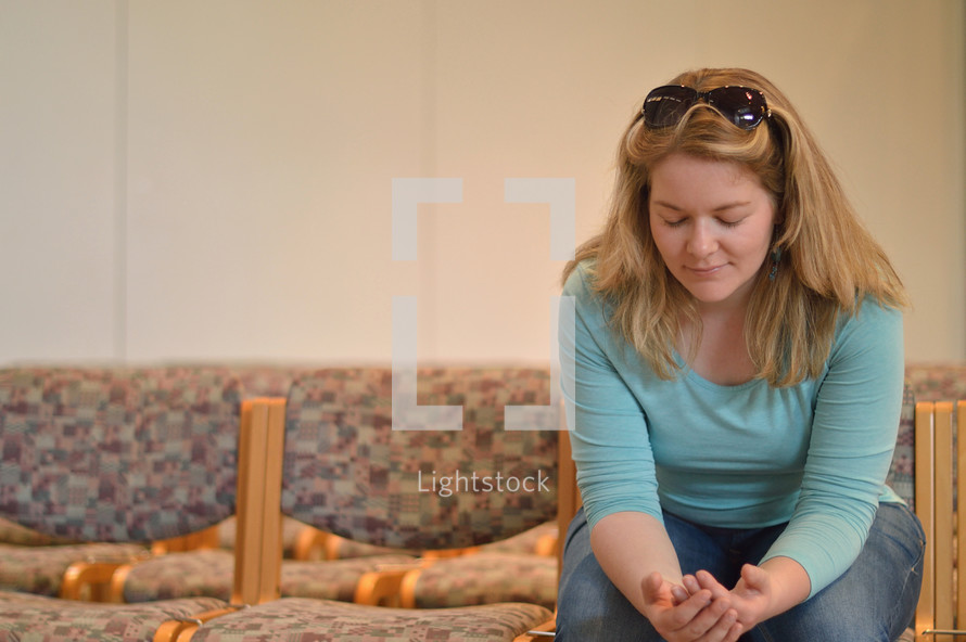 Young blond woman praying while sitting in church