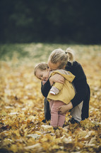 toddler running through fall leaves to get to mom 