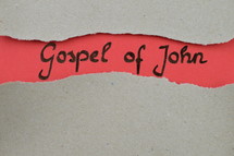 Gospel of John - torn open kraft paper over light red paper with the name of the Gospel of John