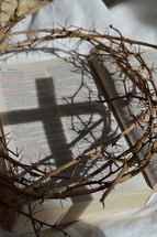 crown of thorns and cross shadow on the pages of a Bible 