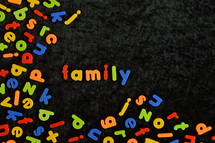 the word FAMILY written with colorful magnetic letters on black ground. 

