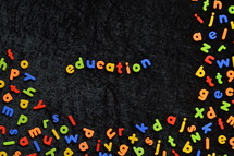 the word EDUCATION written with colorful magnetic letters on black ground 