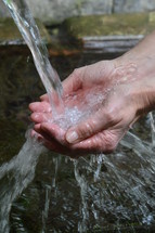 Hands overflowing with streams of water. 
