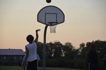 teens playing basketball at sunset 