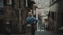 a woman walking through the narrow streets of a European town 