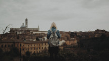 a woman with a backpack with a view of an ancient European city 