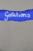 Galatians - torn open kraft paper over intense blue paper with the name of the letter from Paul to the Galations