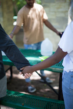 holding hands in prayer around a table at a soup kitchen 
