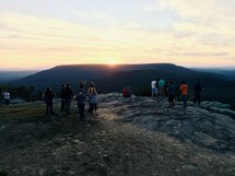 crowd gathered on a mountaintop to watch at sunset