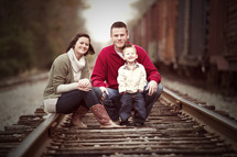 family sitting on railroad tracks 
