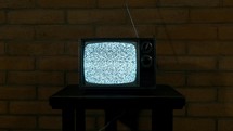 A vintage television set on a stand in a dark room with static